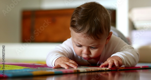 Cute baby lying on floor touching play carpet