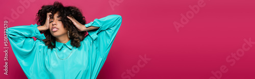 sensual african american woman with closed eyes touching hair isolated on pink, banner.