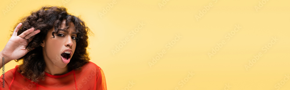curious african american woman with open mouth showing cant hear gesture isolated on yellow, banner. curious african american woman with open mouth showing cant hear gesture isolated on yellow, banner.
