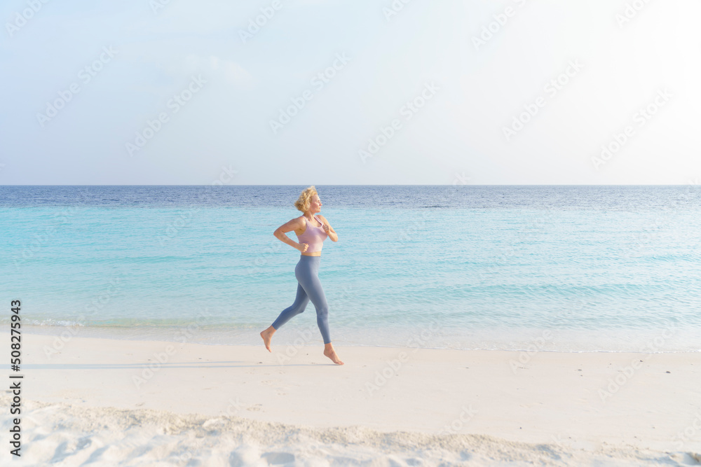 A sporty woman runs along the beach.