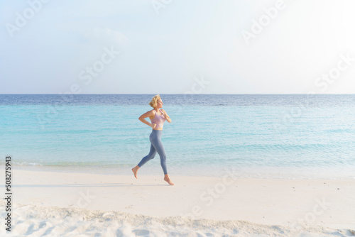 A sporty woman runs along the beach.