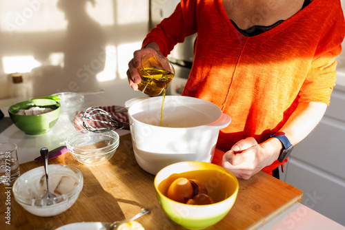 Woman pouring oil into a bowl in the kitchen. photo