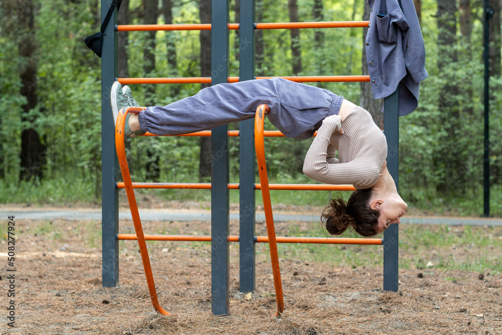 Fototapeta premium Fitness sport girl in fashion sportswear doing yoga fitness exercises on the street, outdoor sports, urban style. Portrait of romantic woman at fairy forest. Girl purple suit. Corduroy fabric