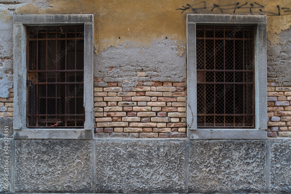 old wall with exposed bricks and two large windows in Italy 