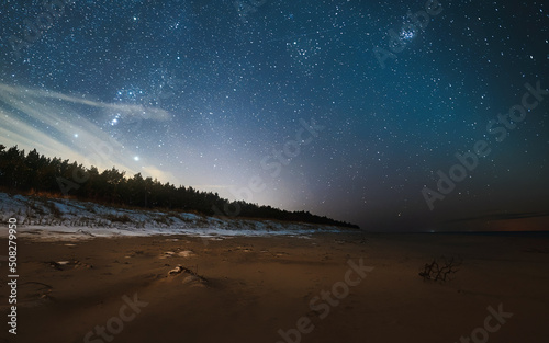 Milky Way galaxy on a sandy sea beach. Star watching during outdoor summer holidays on the seaside.