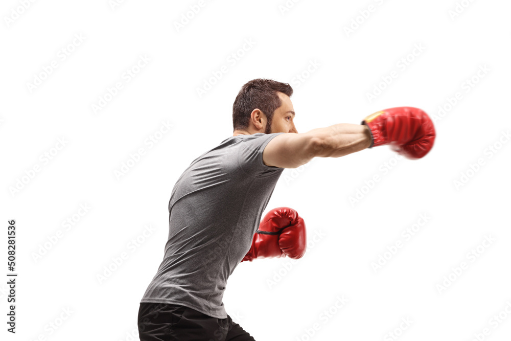 Profile shot of a young man punching with boxing gloves Profile shot of a young man punching with boxing gloves
