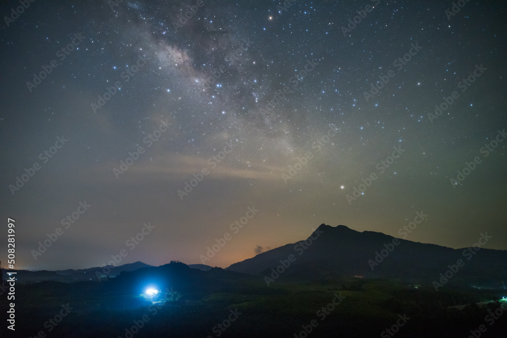milky way on mountain with ligh from house 