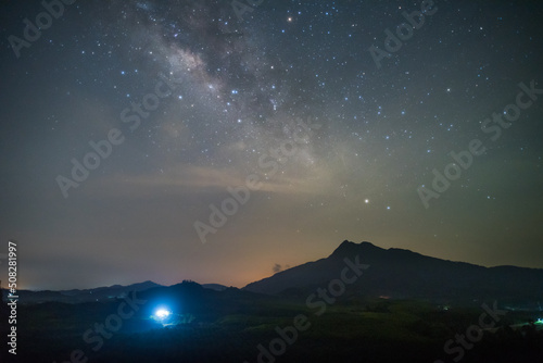milky way on mountain with ligh from house © T i M e L a P s E