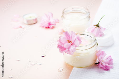 Natural body care cream and pink flowers.