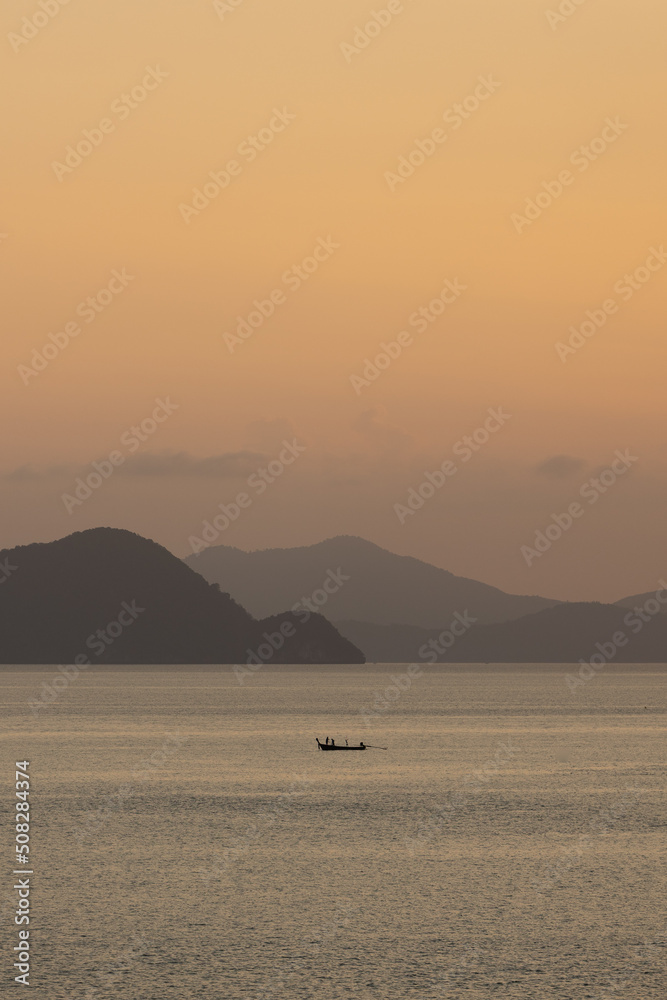 Isolated boat in front of layers of mountains at sunset