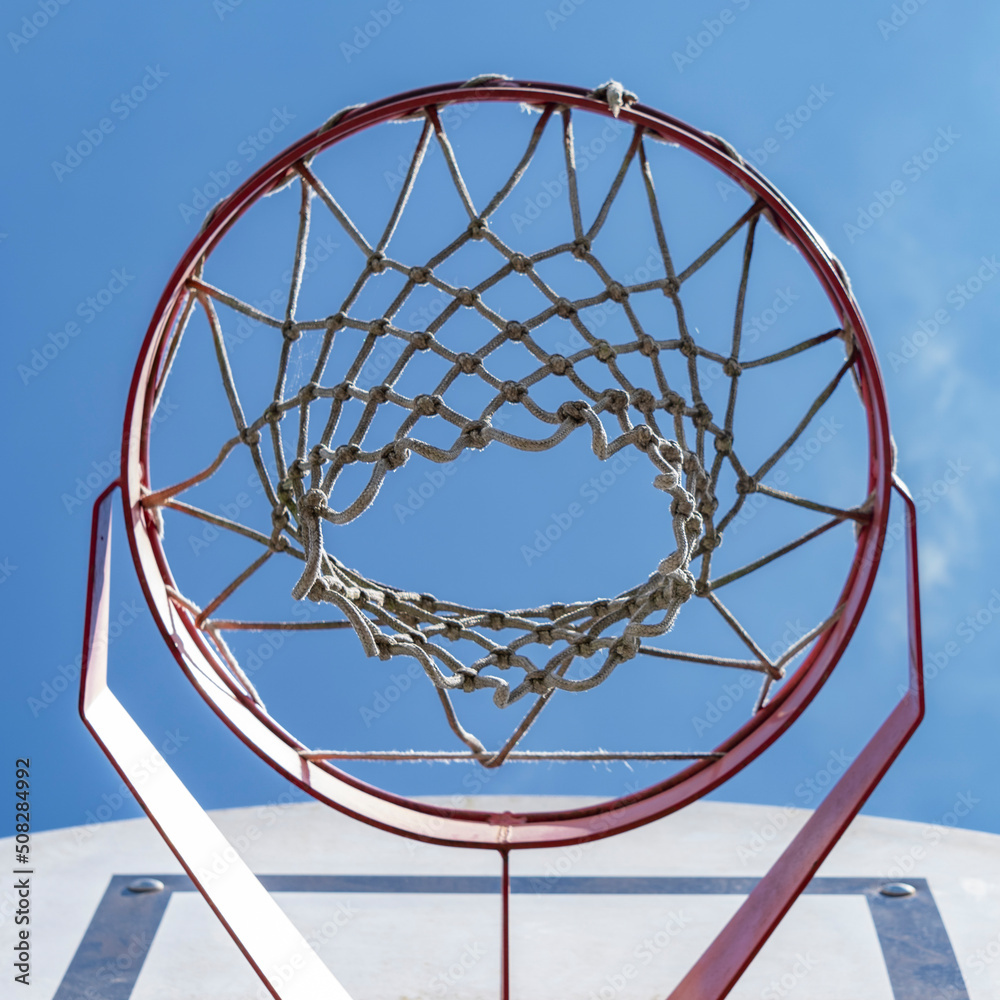 Close-up of a basketball hoop seen from below, blue sky in the background Close-up of a basketball hoop seen from below, blue sky in the background
