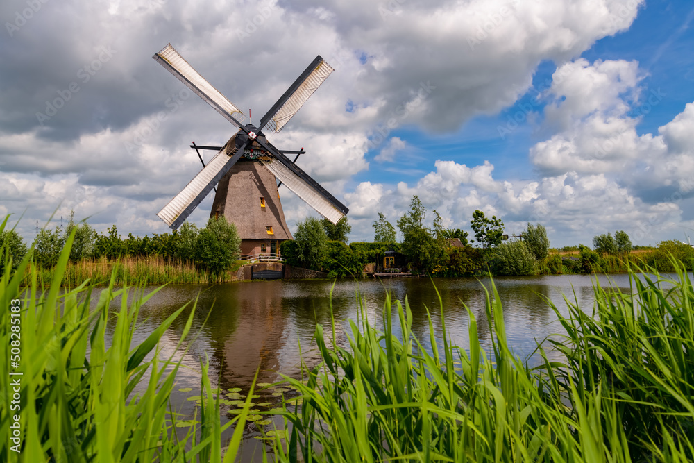 The 19 windmills of “Kinderdijk“ are one of the best-known Dutch tourist sites and world heritage spot. Historic renovated wind water pumps in Alblasserwaard polder, Netherlands on a sunny May day.