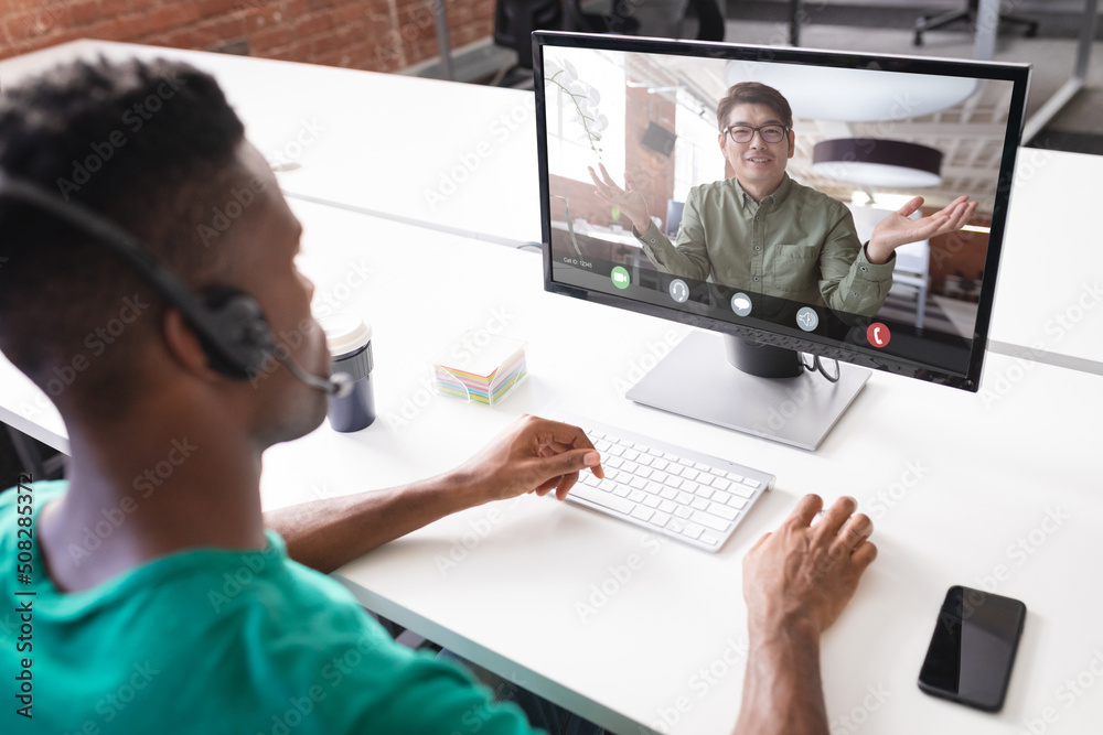 African american and asian businessmen discussing during meeting on video conference in office African american and asian businessmen discussing during meeting on video conference in office