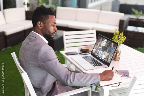African american young businessman using laptop during online meet with multiracial colleagues