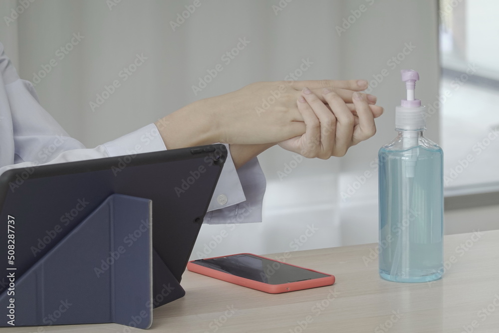 A female worker washes her hands with disinfectant alcohol gel to keep her hands clean and safe from COVID-19. Before picking up your cell phone on the table. Place a bottle of hand sanitizer on table A female worker washes her hands with disinfectant alcohol gel to keep her hands clean and safe from COVID-19. Before picking up your cell phone on the table. Place a bottle of hand sanitizer on table