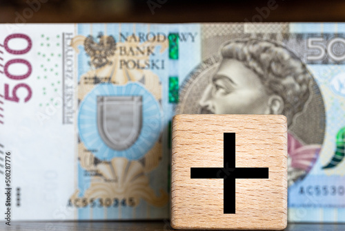 500 plus, Polish social program supporting financially citizens bringing up children, a five hundred zloty banknote and a children's block with a plus sign photo