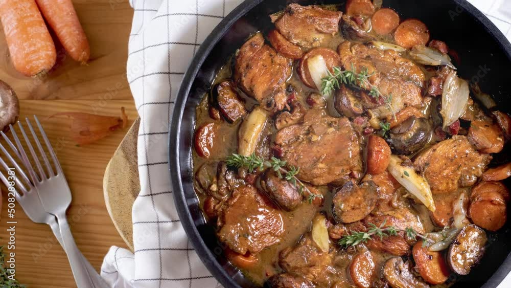 Coq au vin blanc  (Chicken braised in white wine)  in a pan on a wooden surface - stock video