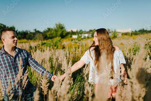 Man and woman talking walk through grass field in countryside.