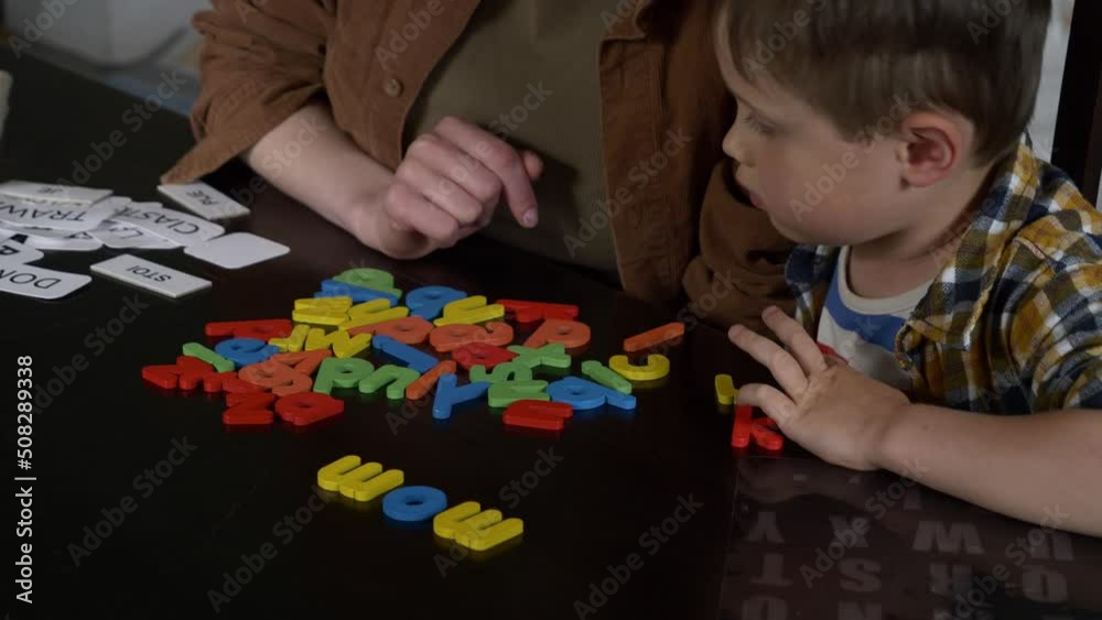 Mom teaches her son how to say the words on the cards at home at the table Mom teaches her son how to say the words on the cards at home at the table