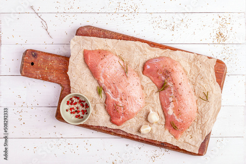 Two raw veal escalope on the old wooden cutting board, top view photo