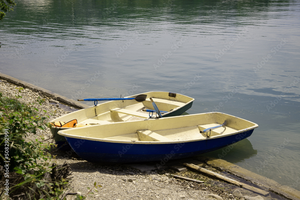 Two wooden boats with oars tied on the shore of the lake. Fishing and tourism.