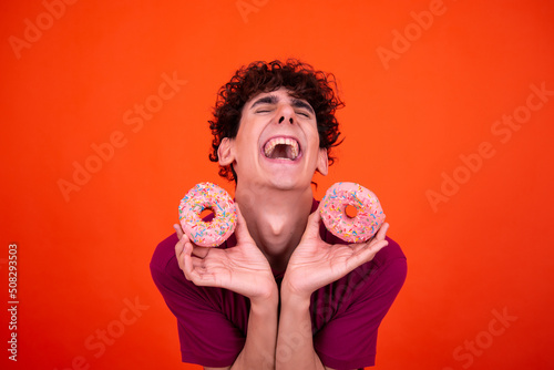 Funny guy eats pink donuts.