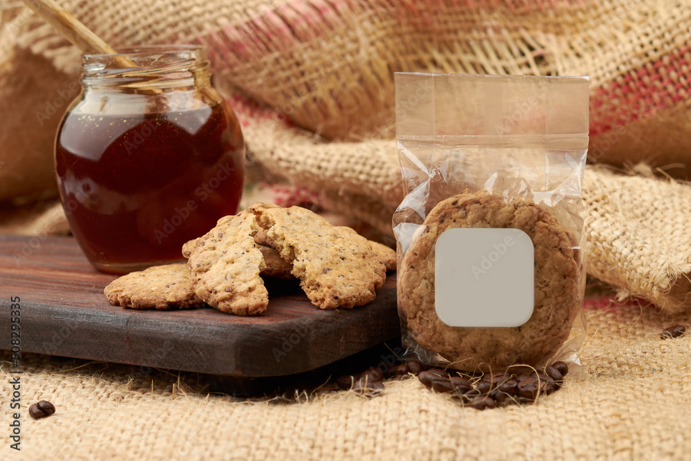 Homemade cookies, in the background honey in a glass, placed on a cutting board, in the background a jute bag made of natural fiber Homemade cookies, in the background honey in a glass, placed on a cutting board, in the background a jute bag made of natural fiber