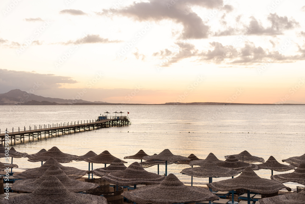 Mediterranean coast with sunbeds and straw sun umbrellas on the sandy beach