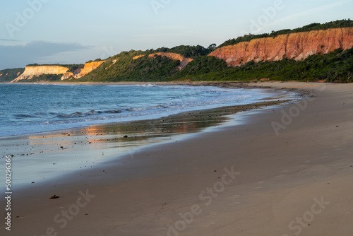 Beautiful beach with cliffs in the background in long exposure photography at sunset