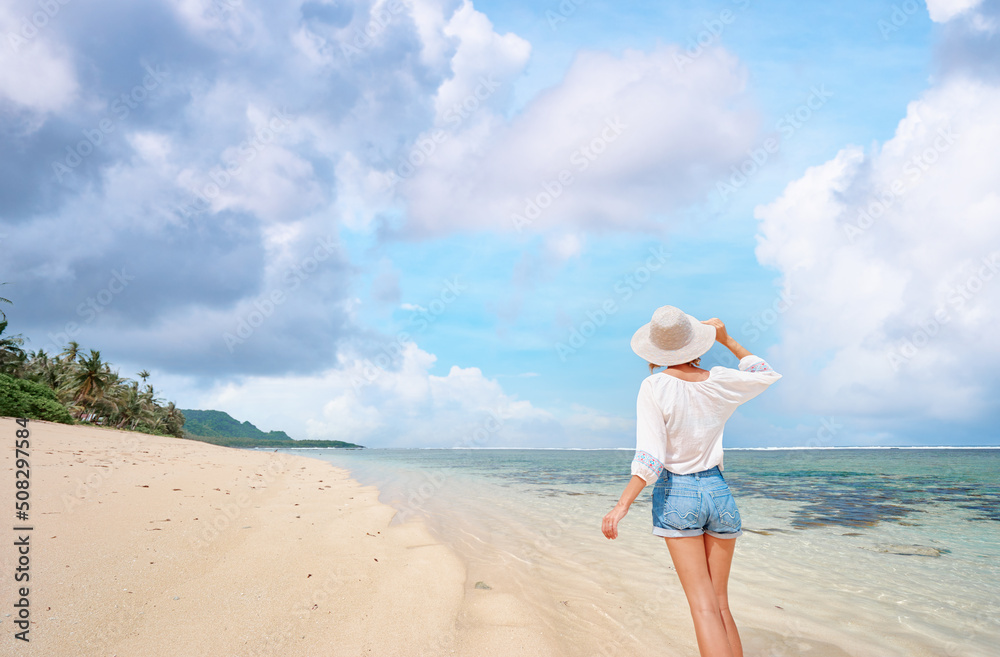 Vacation on the seashore. Back view of young woman walking away on the beautiful tropical white sand beach. Vacation on the seashore. Back view of young woman walking away on the beautiful tropical white sand beach.