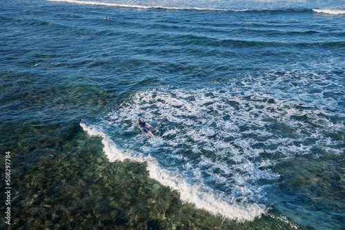 It's time for surfing! Young man swimming on a surf board.
