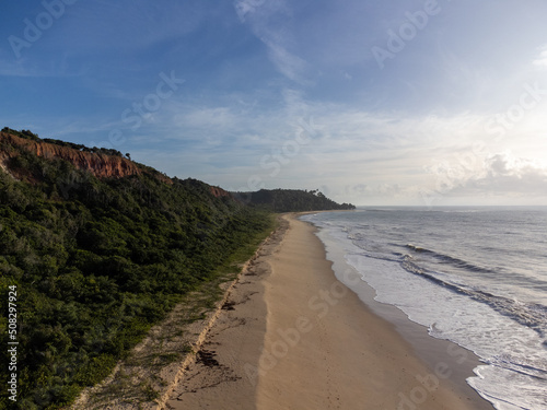 Amazing land cliffs with the golden hour of the rising sun and beautiful beach in Parrancho  Arraial da Ajuda  Bahia  Brazil  South America. Aerial drone view.