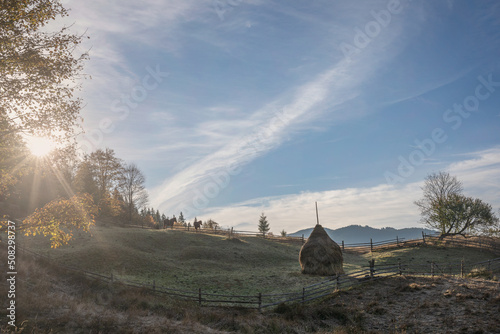 Morning in the Carpathians. Haystack and horses on the background of mountains.