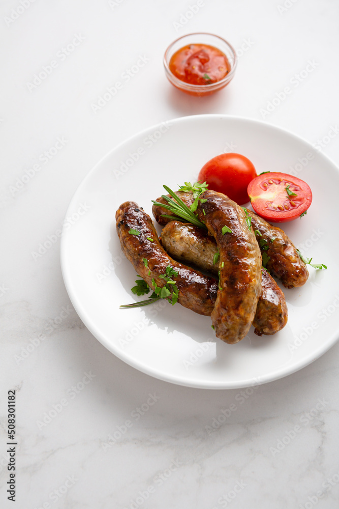 Sausages grilled with herbs, selective focus white plate