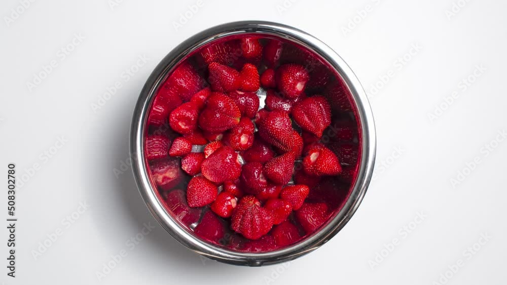 Stop motion concept. Top view of steel bowl with strawberries. White background.