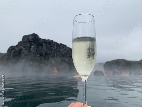 Glass of sparkling wine in pool of Sky Lagoon, geothermal bath in Reykjavik, Iceland.