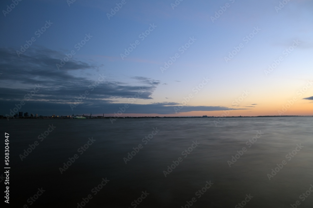 Long exposure of sea water surface with orange sunset and blue sky in Estonia, Tallinn Long exposure of sea water surface with orange sunset and blue sky in Estonia, Tallinn