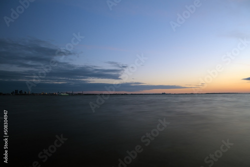 Long exposure of sea water surface with orange sunset and blue sky in Estonia, Tallinn