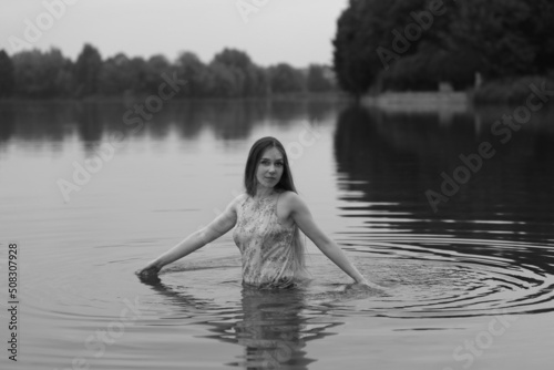 Fototapeta Naklejka Na Ścianę i Meble -  Young woman in wet dress swimming in the lake in black and white