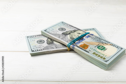 Money, US hundred dollar bills background on white wooden background. Money is scattered on the table. Finance and economics concepts.Money accumulation concept.Currency saving.Investment.Copy space.