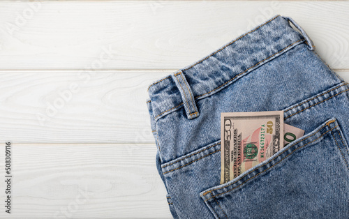 Cash in your pocket. Hundred dollar bills sticking out of the back pocket of blue jeans. Money saving concept. Money saving concept. Saving currency. Investments. Copy space.