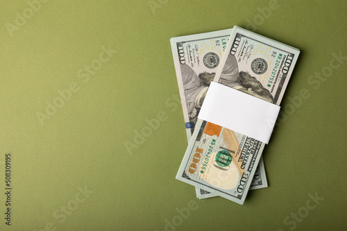 Money, stacks of US hundred dollar bills on an olive background. Money is scattered on the table. Concepts of finance and economy. Money accumulation concept. Saving currency. Investments. Copy space.
