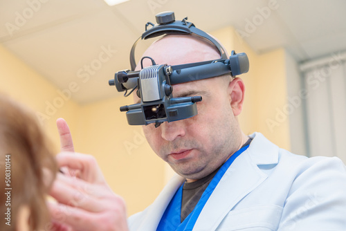 A male ophthalmologist checks the eyesight of an adult woman with a binocular ophthalmoscope photo