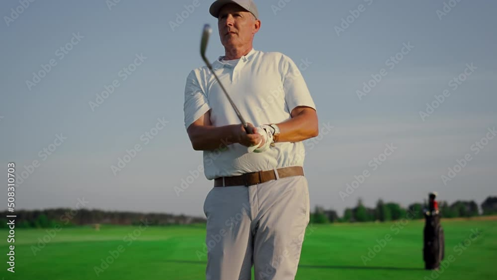 Golf player enjoy hobby on green course. Old man watch golfing ball on fairway. Golf player enjoy hobby on green course. Old man watch golfing ball on fairway.