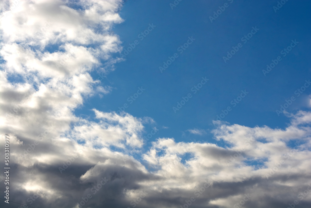 Cumulus and cirrus clouds in the blue sky are illuminated by sunlight. copy space