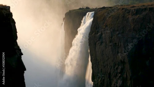 The great Victoria falls waterfall at sunset in Zimbabwe at the border with Zambia. New 7 Natural Wonders of the World. Mosi-oa-Tunya on river Zambezi. photo