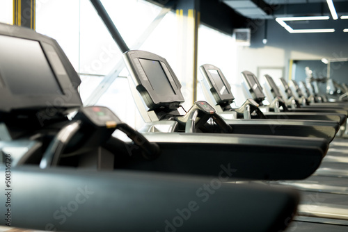 Row of treadmills for running exercises in modern fitness center