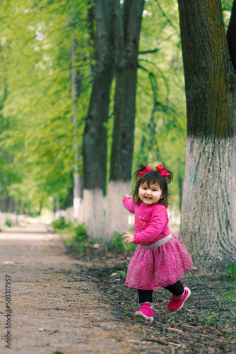 little girl accompanied by her mother on a beautiful summer day walking through a small forest inside the city