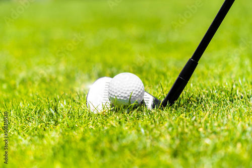 Golf ball and golf club on green grass on golf course