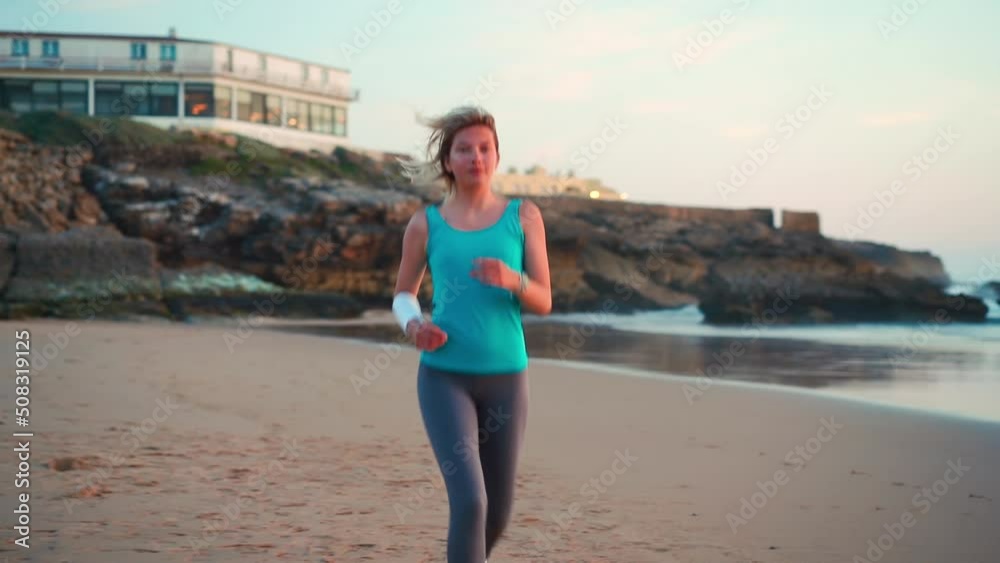 Sporty blonde woman running ocean beach. Young caucasian female exercising outdoors running seashore. Concept of healthy running and outdoors exercise. Active, sporty athlete jogging. Dusk Sporty blonde woman running ocean beach. Young caucasian female exercising outdoors running seashore. Concept of healthy running and outdoors exercise. Active, sporty athlete jogging. Dusk